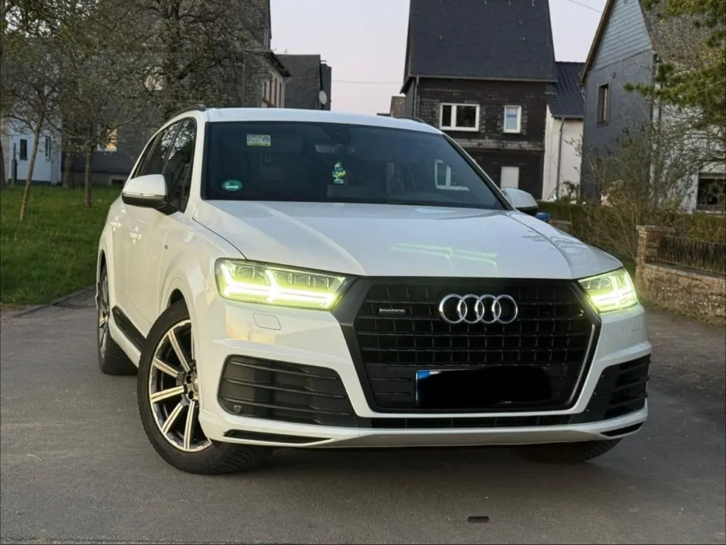 Weißer Audi Q7 mit eingeschaltetem Tagfahrlicht