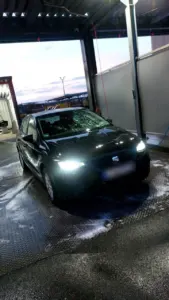Seat Ibiza mit eingeschalteten Scheinwerfern in der Waschanlage am Abend