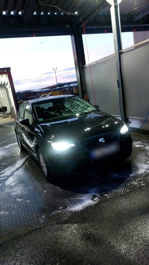 Seat Ibiza mit eingeschalteten Scheinwerfern in der Waschanlage am Abend